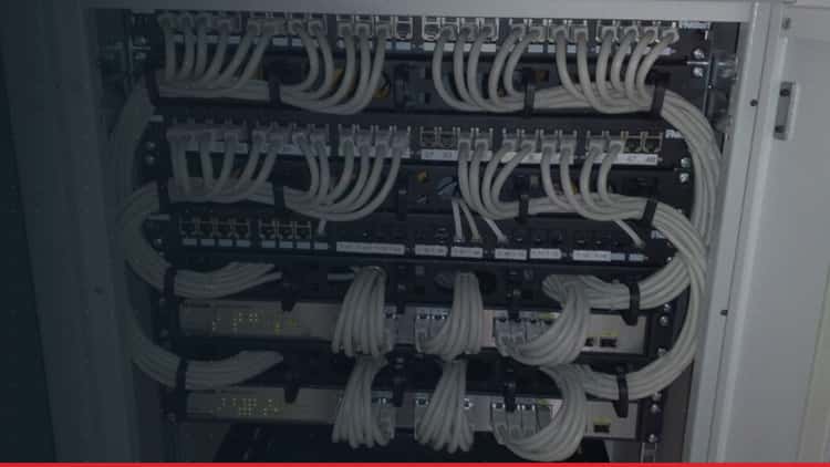 A network cabinet with patch panels, grey cables and two switches